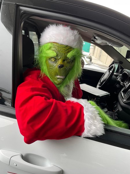 The Grinch takes a ride in a police car.